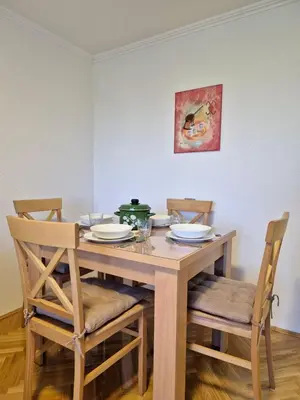 a dining room table with four chairs and a green pot on it at Apartman Alemina - mirna lokacija blizu centra, priroda i privatnost in Cazin