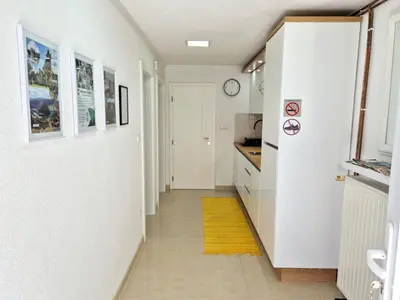 a hallway with a white kitchen with a yellow rug at Apartman Alemina - mirna lokacija blizu centra, priroda i privatnost in Cazin