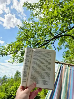 a person holding a book in front of a tree at Apartman Alemina - mirna lokacija blizu centra, priroda i privatnost in Cazin