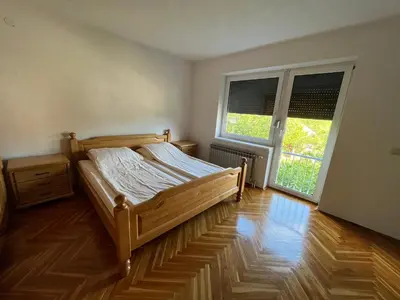 a bedroom with a wooden bed and two windows at Althea Home & Wellness in Bihać