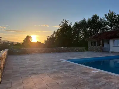 a backyard with a swimming pool and the sunset at Althea Home & Wellness in Bihać