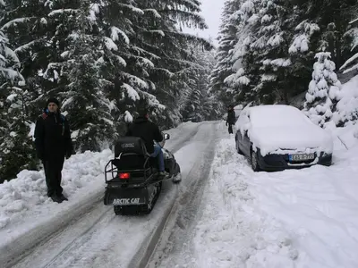 a man driving a snowmobile down a snow covered road at Vlašićki Konak in Vlasic