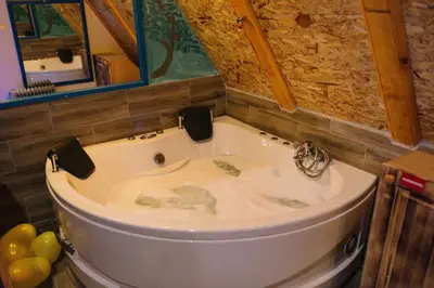 a bath tub in a bathroom with a stone wall at Etno Village Dolina Sreće in Vitez