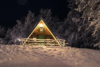 a log cabin in the snow at night at Etno Village Dolina Sreće in Vitez