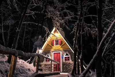 a log cabin with a red door in the snow at Etno Village Dolina Sreće in Vitez