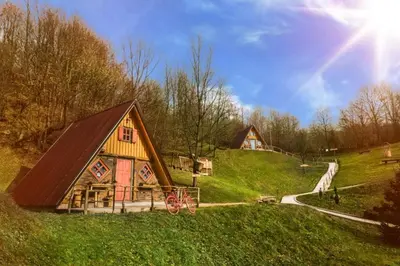a barn on a hill with the sun in the sky at Etno Village Dolina Sreće in Vitez
