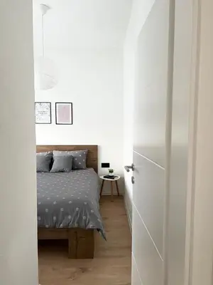 a bedroom with a bed and a white wall at Home Away From Home in Jajce