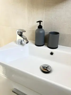 a white bathroom sink with a soap dispenser on it at Home Away From Home in Jajce