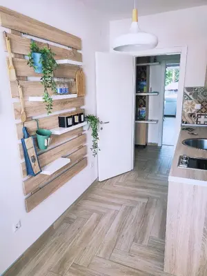 a kitchen with white walls and wooden floors at Apartman Lena in Tuzla