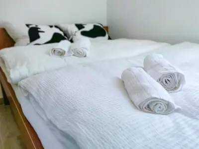 two beds with white sheets and rolled towels on them at Apartman “Centar Jajce “ in Jajce
