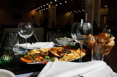 a table with a plate of food and wine glasses at Hotel Terme Ozren in Bosansko Petrovo Selo