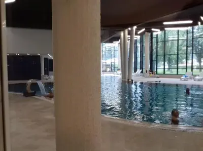 a pool in a building with a person in the water at Street View Apartman in Fojnica