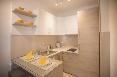 a small kitchen with white cabinets and a sink at Jelena Apartment II in Doboj
