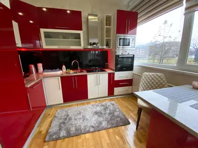 a kitchen with red cabinets and a large window at Apartman 