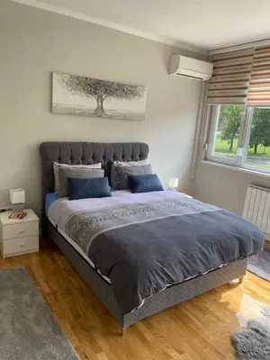 a bedroom with a large bed with blue pillows at Apartman 
