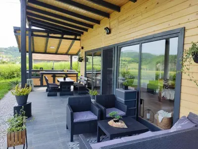 an outdoor patio with chairs and tables and glass doors at Residence Wood Pool & SPA in Visoko