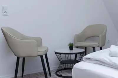 two white chairs sitting next to a bed and a table at Pansion A&M Vlašić in Vlasic