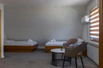 a room with two beds and a table and chairs at Pansion A&M Vlašić in Vlasic