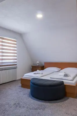a bedroom with two beds and a blue ottoman at Pansion A&M Vlašić in Vlasic