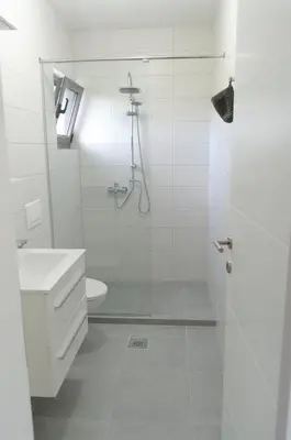 a white bathroom with a shower and a sink at Villa Una Sunset in Bihać
