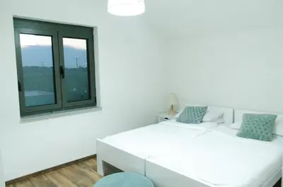 a white bedroom with a bed and a window at Villa Una Sunset in Bihać
