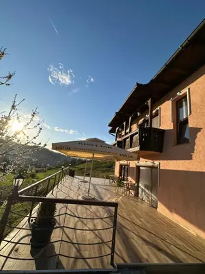a wooden deck with a table and umbrella on a building at The View Apartment in Visoko