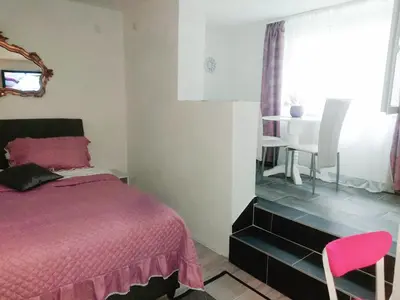 a bedroom with a pink bed and a table at APARTMAN ANDREA 4 in Banja Luka