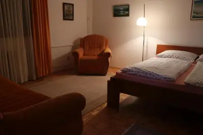 a bedroom with a bed and a chair and a lamp at Apartman UNA Travnik in Travnik