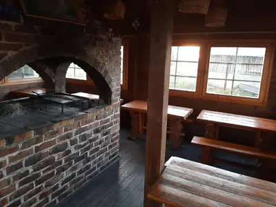 a brick oven in a room with benches and windows at Apartman Lari in Vlasic