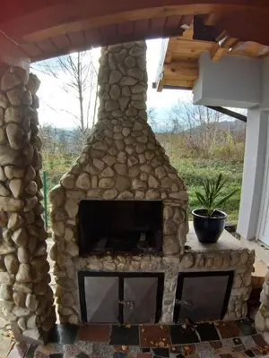 a large stone fireplace in a patio with a roof at COUNTRY HOUSE in Bihać
