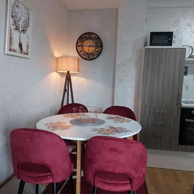 a dining room table with chairs and a clock on the wall at Apartman Zlaja Vlašić in Vlasic