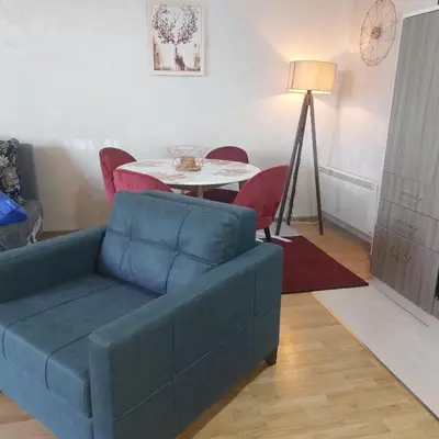 a living room with a blue couch and a table at Apartman Zlaja Vlašić in Vlasic