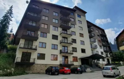 a large building with cars parked in front of it at Apartman Zlaja Vlašić in Vlasic