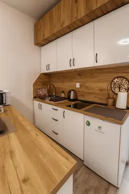 a kitchen with white cabinets and a wooden counter top at Alpin Apartments Vlašić in Vlasic