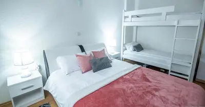 a bedroom with a white bed with pink pillows at Alpin Apartments Vlašić in Vlasic