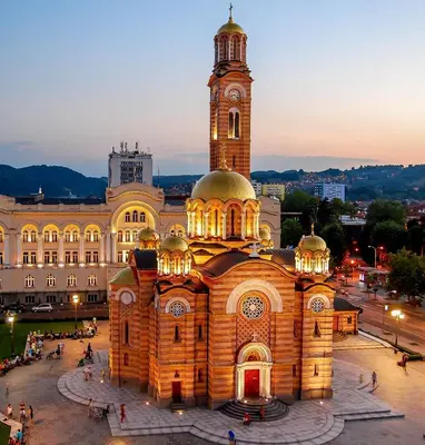 a large building with a clock tower at dusk at All White in Banja Luka