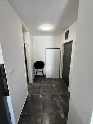 a hallway with a black chair and a door at Apartman CITY CENTER 2 in Prijedor