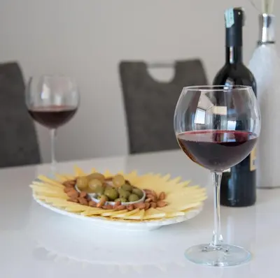 a glass of wine and a plate of food on a table at Apartman Ante in Livno