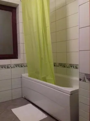 a bathroom with a tub with a green shower curtain at City View Apartment in Fojnica
