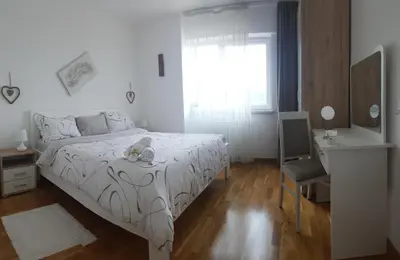 a white bedroom with a bed and a desk and a window at Fantasy apartment Tuzla in Tuzla