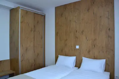 a bedroom with a wooden headboard and two white pillows at ATOS Centar in Čelinac