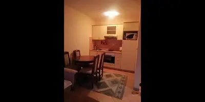 a room with a table and a kitchen with a refrigerator at Apartman SARA Babanovac Vlašić in Travnik