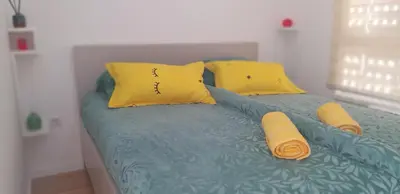 a bed with two yellow pillows on top of it at Apartman Amor in Tuzla