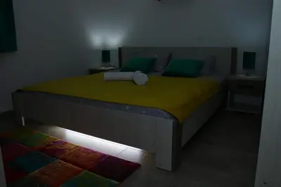 a bedroom with a large bed with green pillows at Apartman 