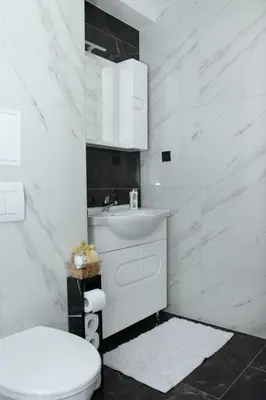 a white bathroom with a toilet and a sink at Apartman 