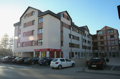 a large building with cars parked in a parking lot at Apartman 