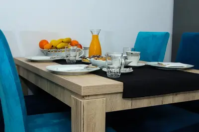 a wooden table with plates and glasses and a bowl of fruit at Apartman 