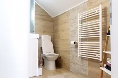a bathroom with a toilet and wooden walls at Kuća za odmor ANA in Kupres