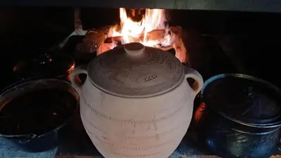 a large white vase sitting in front of a fire at Log Cabins Jovicic in Bosanska Dubica