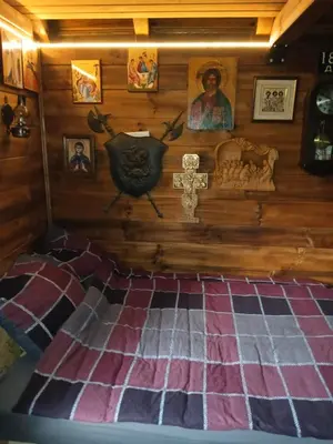 a room with a wall with a cross and a bed at Log Cabins Jovicic in Bosanska Dubica